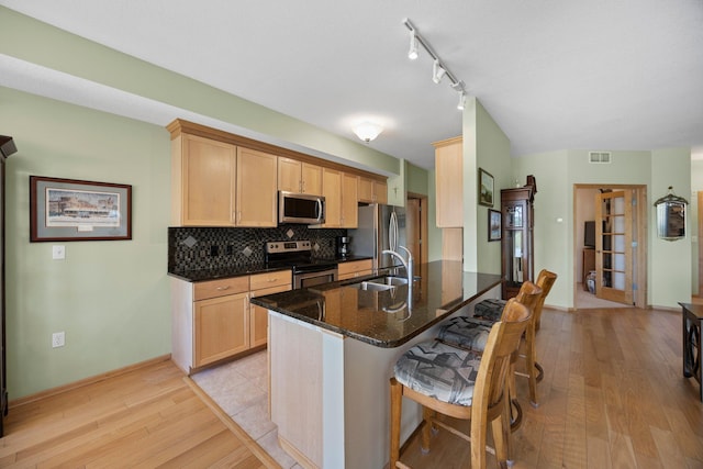630 Main St N Unit 202, Stillwater, MN 55082 - kitchen with stainless steel appliances, a sink, light wood-type flooring, a breakfast bar area, and tasteful backsplash