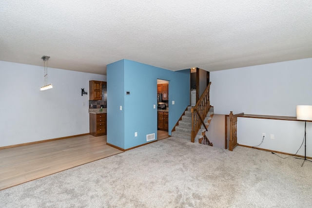 unfurnished room with a textured ceiling and carpet flooring