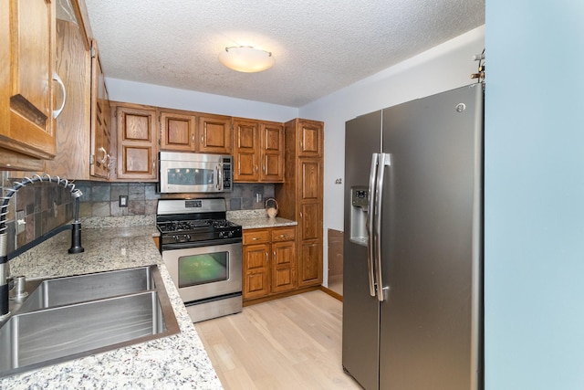 kitchen featuring a textured ceiling, appliances with stainless steel finishes, decorative backsplash, and sink