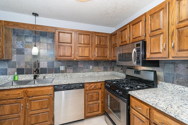 kitchen featuring light stone countertops, appliances with stainless steel finishes, sink, hanging light fixtures, and light tile patterned floors