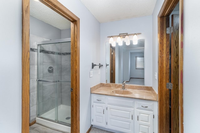 bathroom with a textured ceiling, an enclosed shower, and vanity