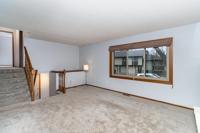 empty room with a textured ceiling and carpet floors