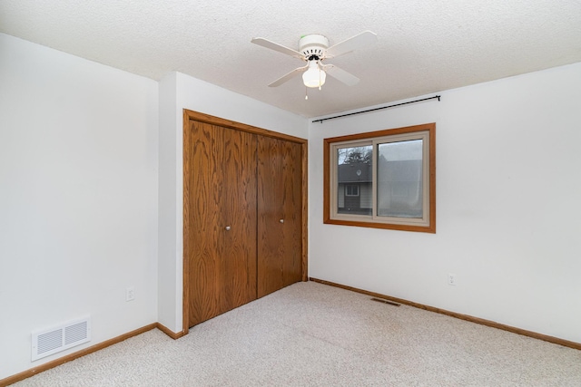 unfurnished bedroom with ceiling fan, light colored carpet, a textured ceiling, and a closet