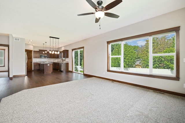 unfurnished living room with sink, dark hardwood / wood-style floors, a wealth of natural light, and ceiling fan