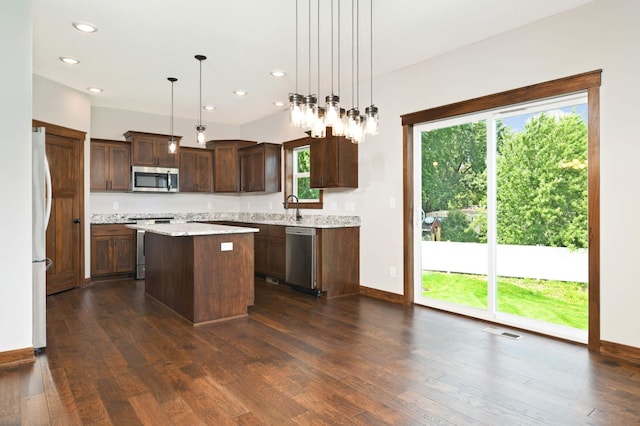 kitchen featuring a wealth of natural light, a center island, hanging light fixtures, and appliances with stainless steel finishes