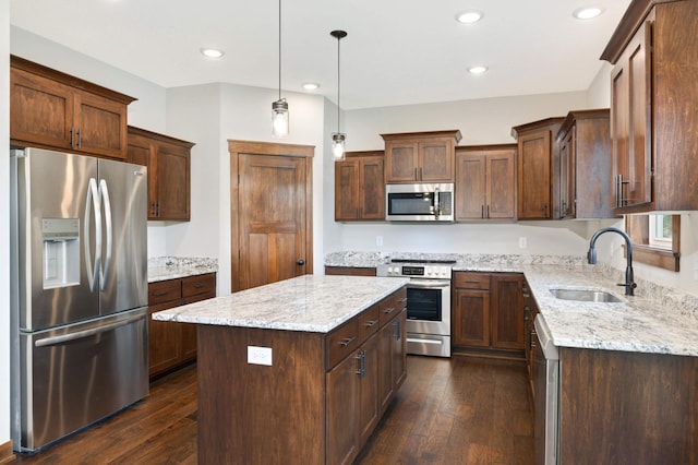 kitchen with sink, a center island, dark wood-type flooring, light stone counters, and appliances with stainless steel finishes