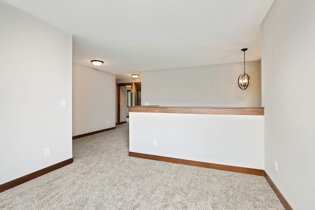 spare room featuring carpet and a chandelier