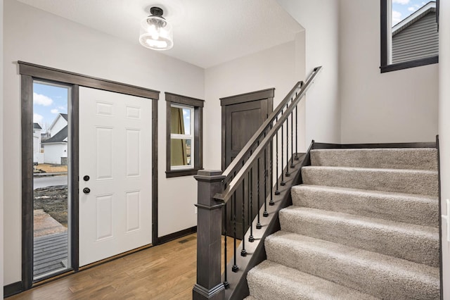 entrance foyer with stairway, visible vents, baseboards, and wood finished floors