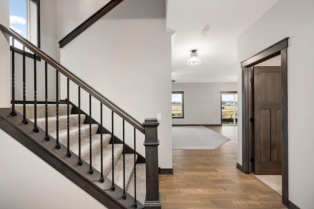 foyer entrance with a towering ceiling, baseboards, and wood finished floors