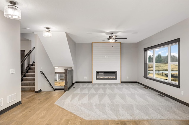 unfurnished living room featuring baseboards, a fireplace, visible vents, and wood finished floors