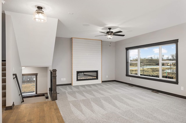 unfurnished living room with carpet floors, visible vents, a fireplace, and baseboards