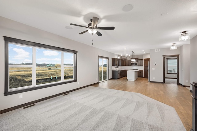 unfurnished living room featuring light wood-style flooring, visible vents, and baseboards