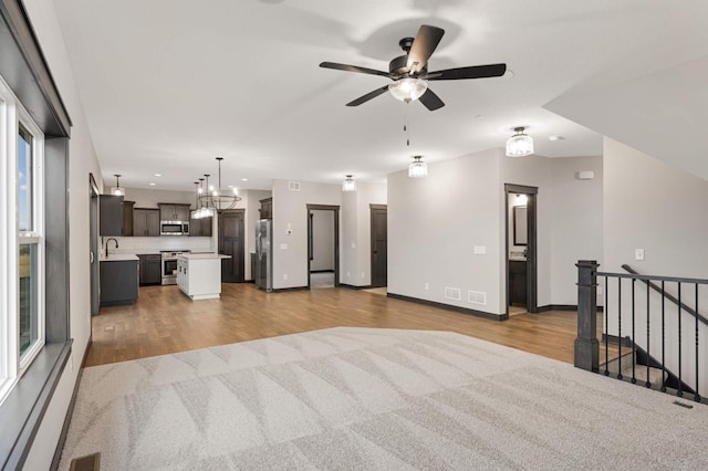 unfurnished living room with a sink, wood finished floors, visible vents, and a ceiling fan