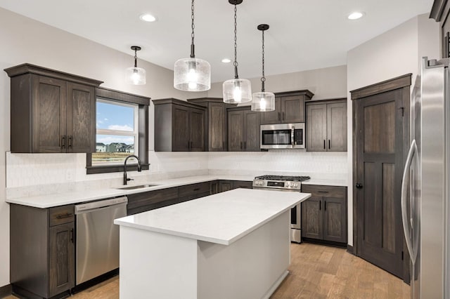 kitchen with light wood-style flooring, a sink, dark brown cabinets, appliances with stainless steel finishes, and tasteful backsplash