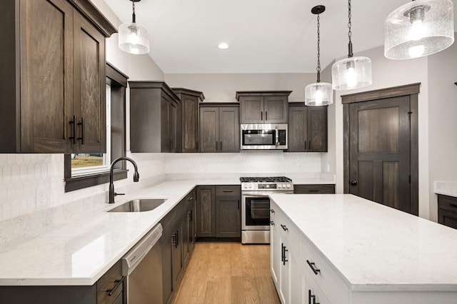 kitchen with a center island, stainless steel appliances, a sink, dark brown cabinets, and light wood-type flooring