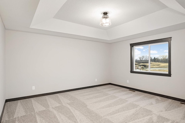 unfurnished room featuring carpet, a raised ceiling, and baseboards