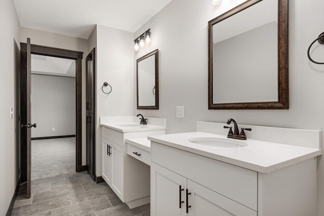 bathroom with baseboards, two vanities, and a sink