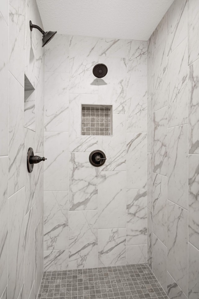 full bath featuring a tile shower and a textured ceiling