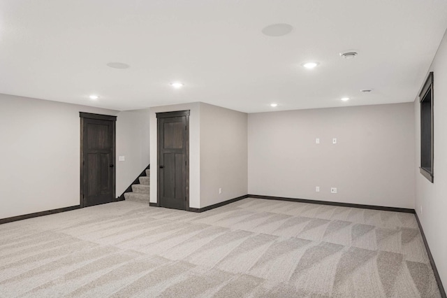 finished basement with light carpet, baseboards, and stairs