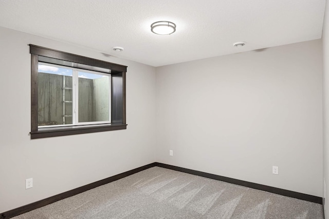 spare room featuring carpet floors, baseboards, and a textured ceiling