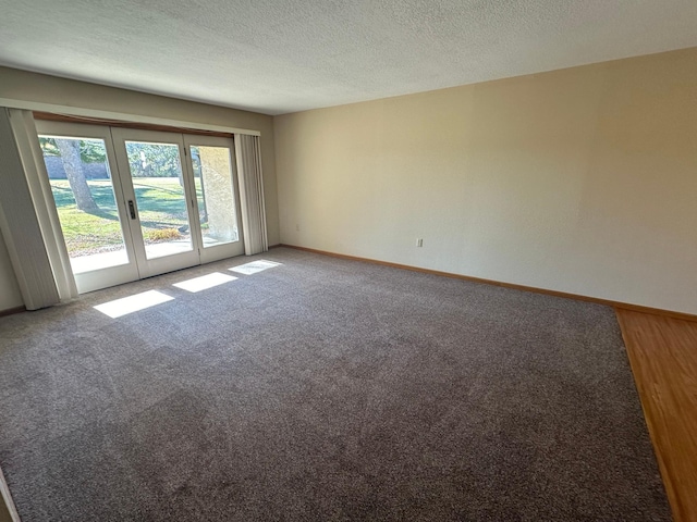 spare room with french doors, carpet floors, and a textured ceiling