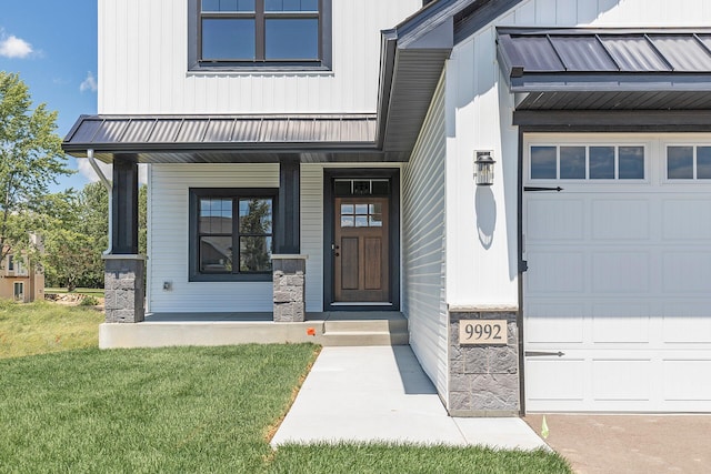 entrance to property featuring a porch, a garage, and a yard