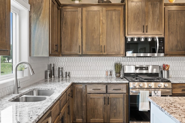 kitchen featuring light stone countertops, appliances with stainless steel finishes, backsplash, and sink