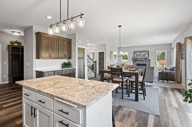 kitchen featuring pendant lighting, tasteful backsplash, a kitchen island, dark hardwood / wood-style flooring, and white cabinetry