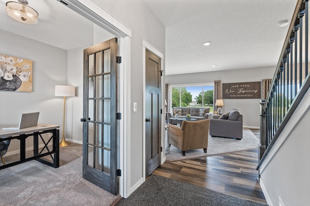 hallway with a textured ceiling, dark wood-type flooring, and french doors