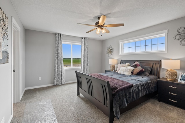 bedroom featuring a textured ceiling, light colored carpet, and ceiling fan