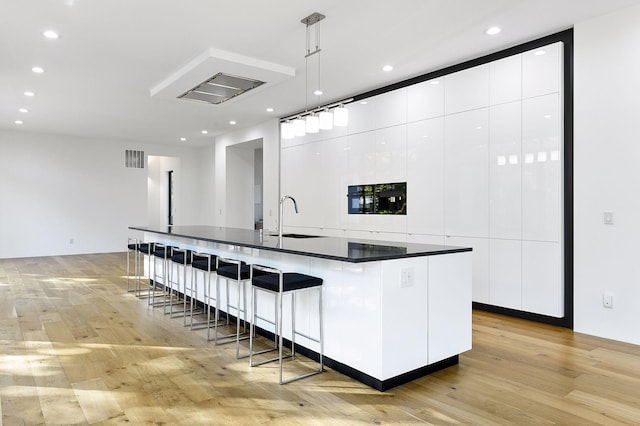 kitchen with pendant lighting, sink, a breakfast bar, a spacious island, and white cabinets