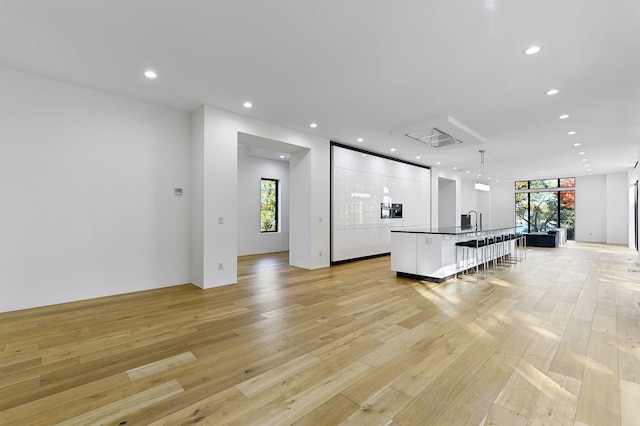 kitchen with a breakfast bar, sink, light hardwood / wood-style floors, floor to ceiling windows, and a center island with sink