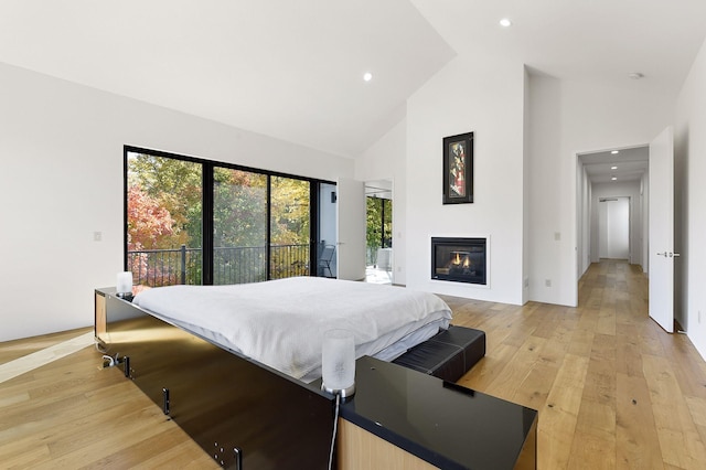 bedroom with access to outside, high vaulted ceiling, and light wood-type flooring