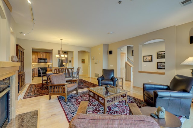 living room with wine cooler, light hardwood / wood-style flooring, a premium fireplace, and a chandelier