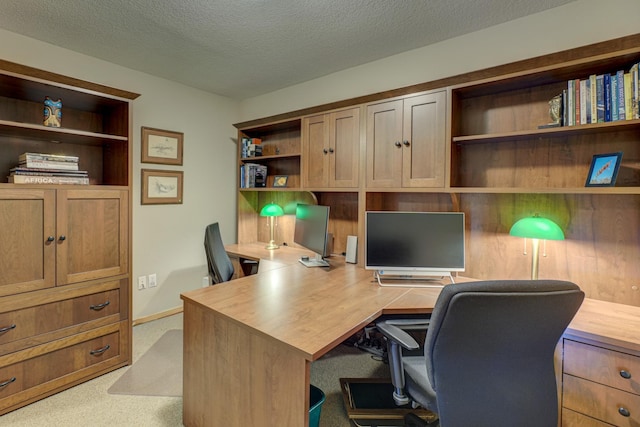 carpeted home office featuring a textured ceiling