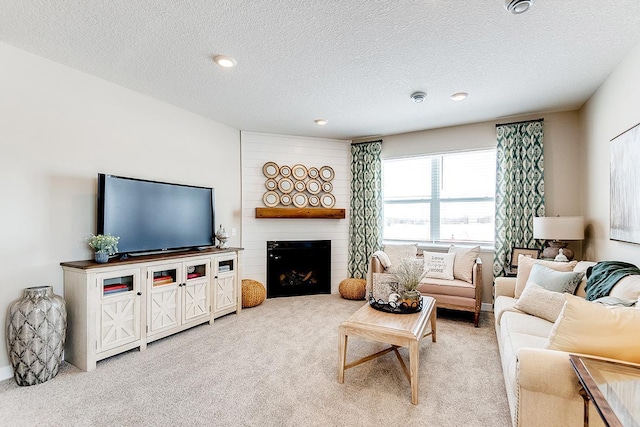 carpeted living room with a textured ceiling and a large fireplace