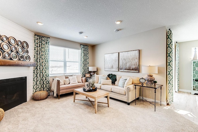 carpeted living room with a textured ceiling and a large fireplace