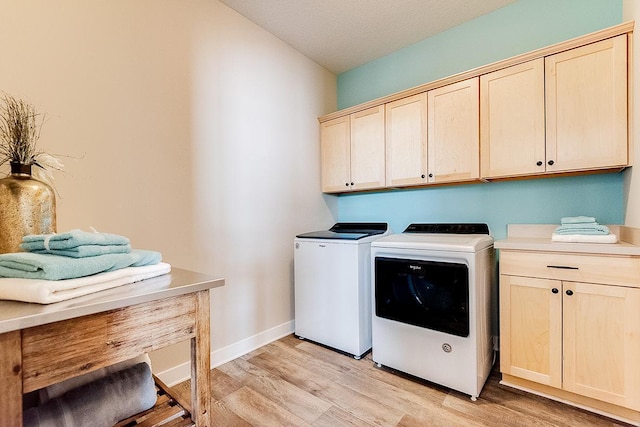 laundry room with cabinets, independent washer and dryer, light wood-type flooring, and a textured ceiling