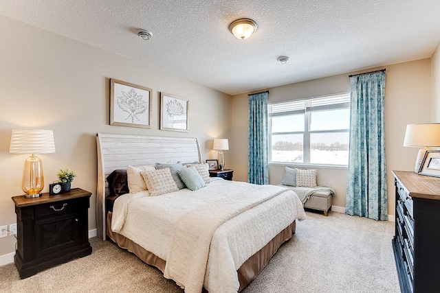 bedroom with light carpet, a textured ceiling, and baseboards