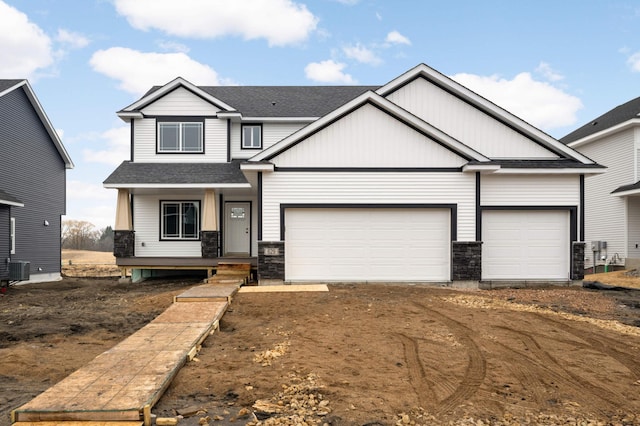 craftsman-style home with dirt driveway, central air condition unit, a shingled roof, covered porch, and a garage