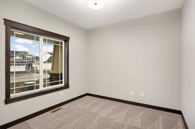 carpeted empty room featuring visible vents and baseboards