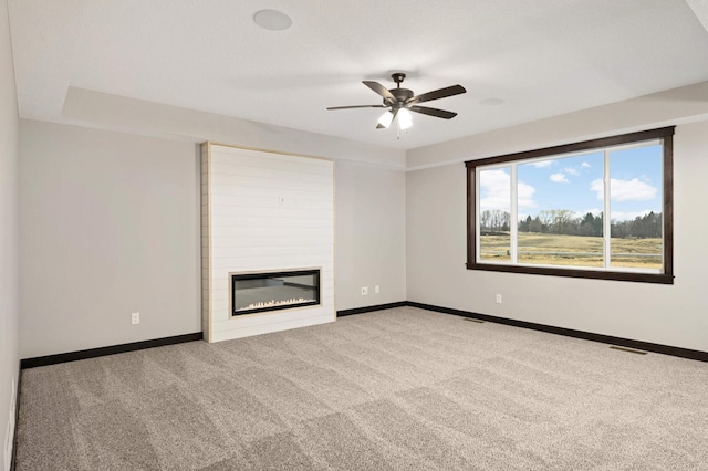 unfurnished living room featuring carpet floors, a large fireplace, and baseboards