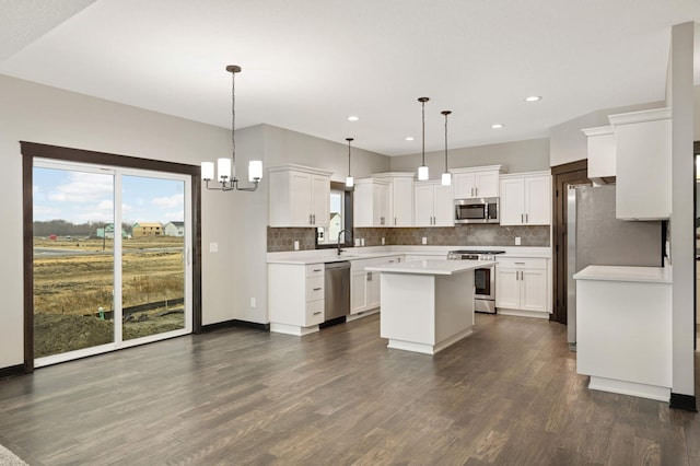 kitchen featuring a center island, light countertops, backsplash, appliances with stainless steel finishes, and dark wood-type flooring