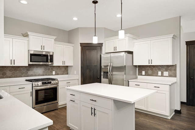 kitchen with white cabinets, dark wood-type flooring, decorative light fixtures, stainless steel appliances, and light countertops