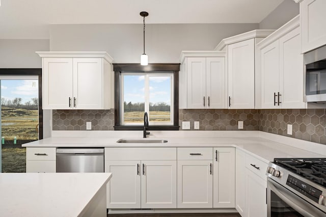 kitchen featuring appliances with stainless steel finishes, light countertops, white cabinets, and a sink