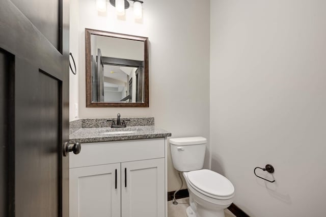 bathroom with baseboards, vanity, and toilet