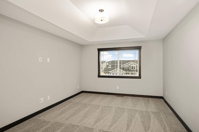 empty room with carpet, baseboards, visible vents, and a tray ceiling