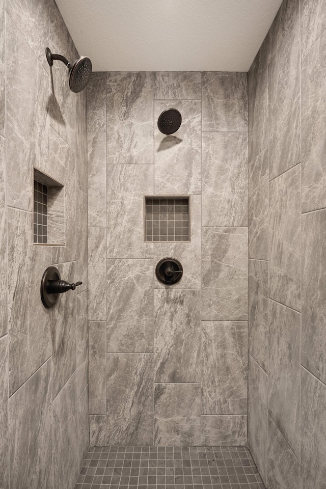 bathroom with a textured ceiling and a tile shower