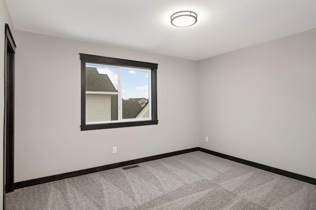 carpeted spare room with visible vents, a textured ceiling, and baseboards