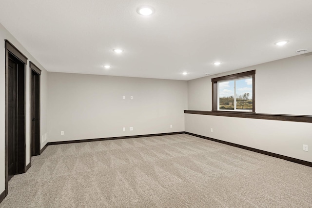 spare room featuring baseboards, recessed lighting, and light colored carpet